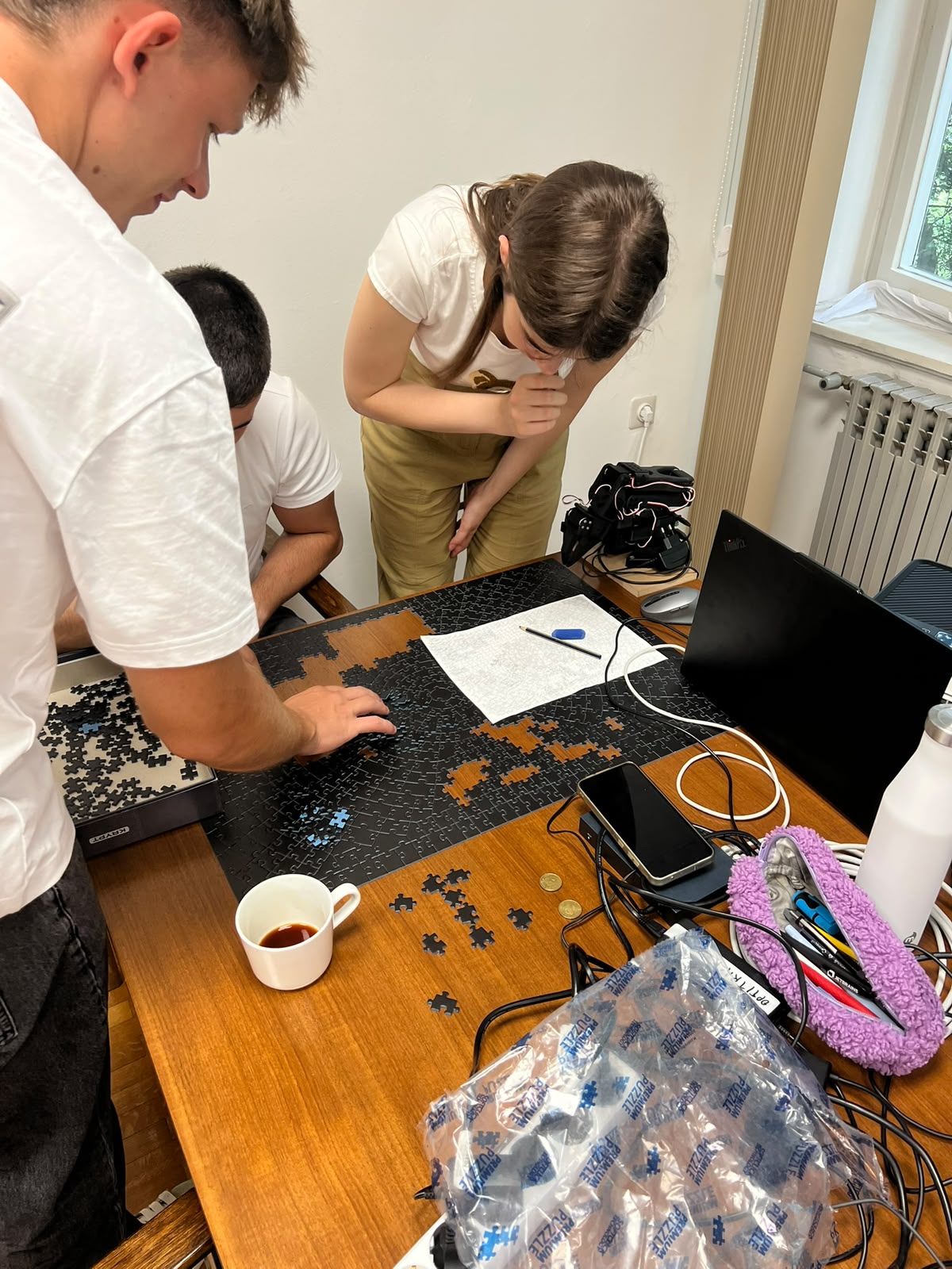 Students working together on a jigsaw puzzle at a desk at MARBLE headquarters, pointing out where a piece fits